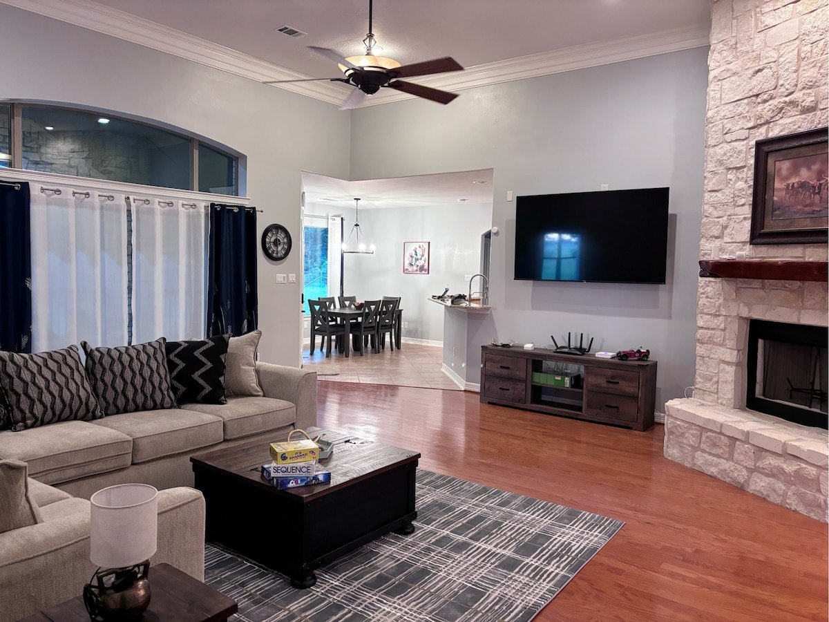 Spacious living room with high ceilings, 75-inch smart TV, cozy couch, and fire area